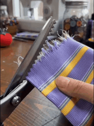 Pinking shears cutting a loose frayed fabric edge