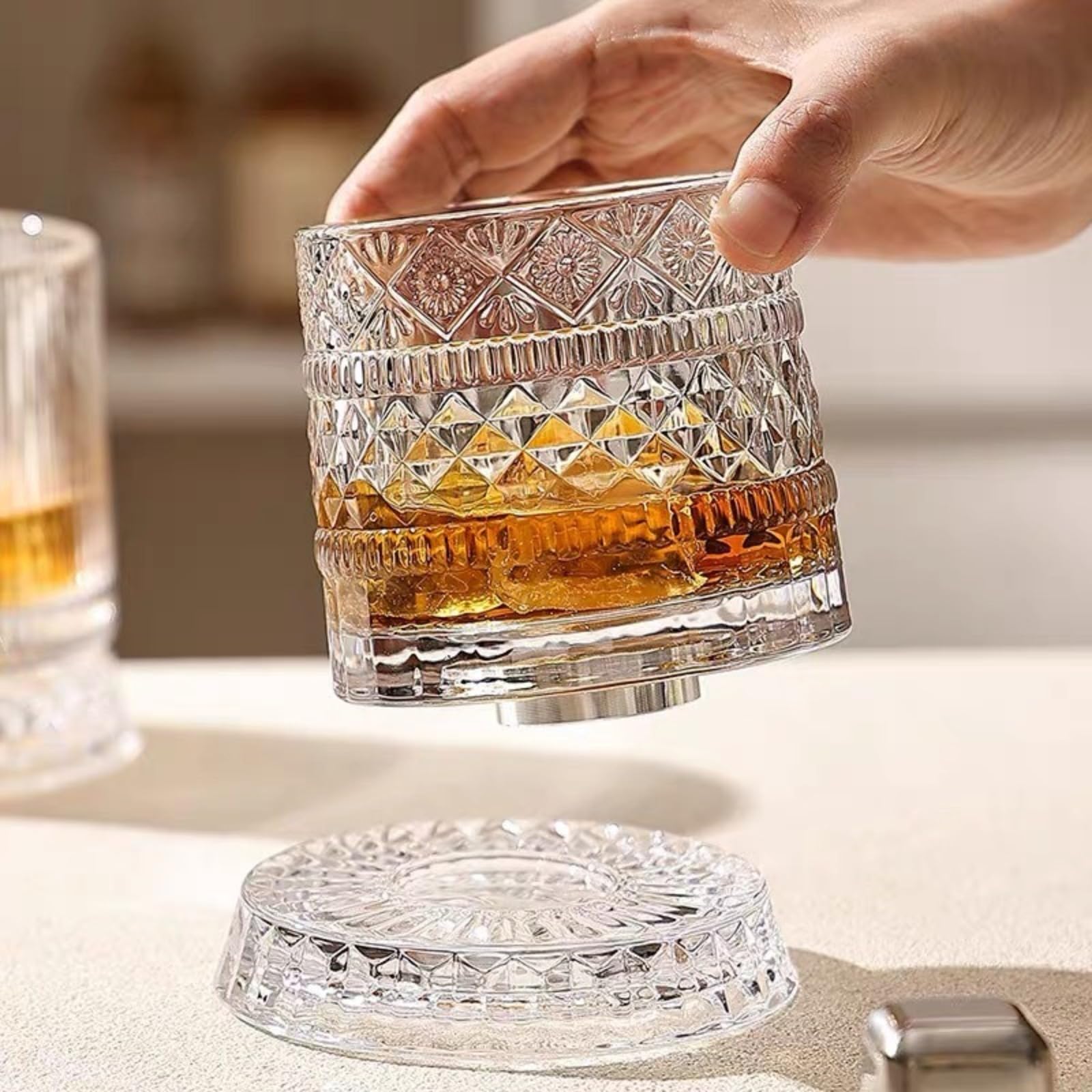 Whiskey glass being lifted from its rotating crystal base