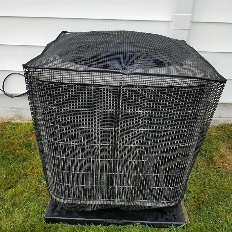 Black mesh protector installed over an outdoor air conditioner beside a house