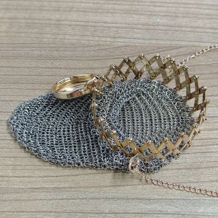 Close-up of gold ribbed metal frame and chain clasp on mesh purse